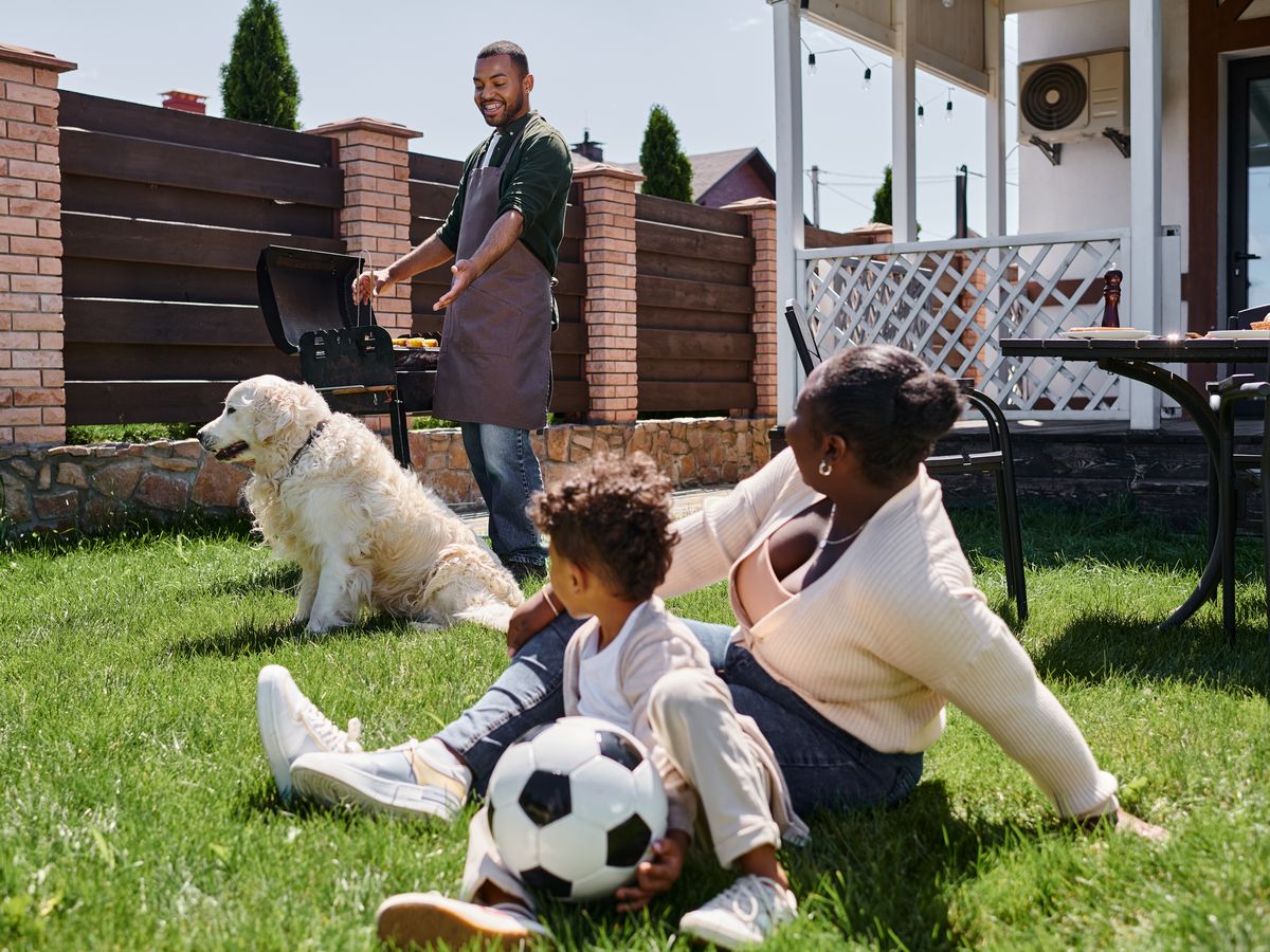 A family and their dog relaxing on a thick green lawn behind a North Georgia home